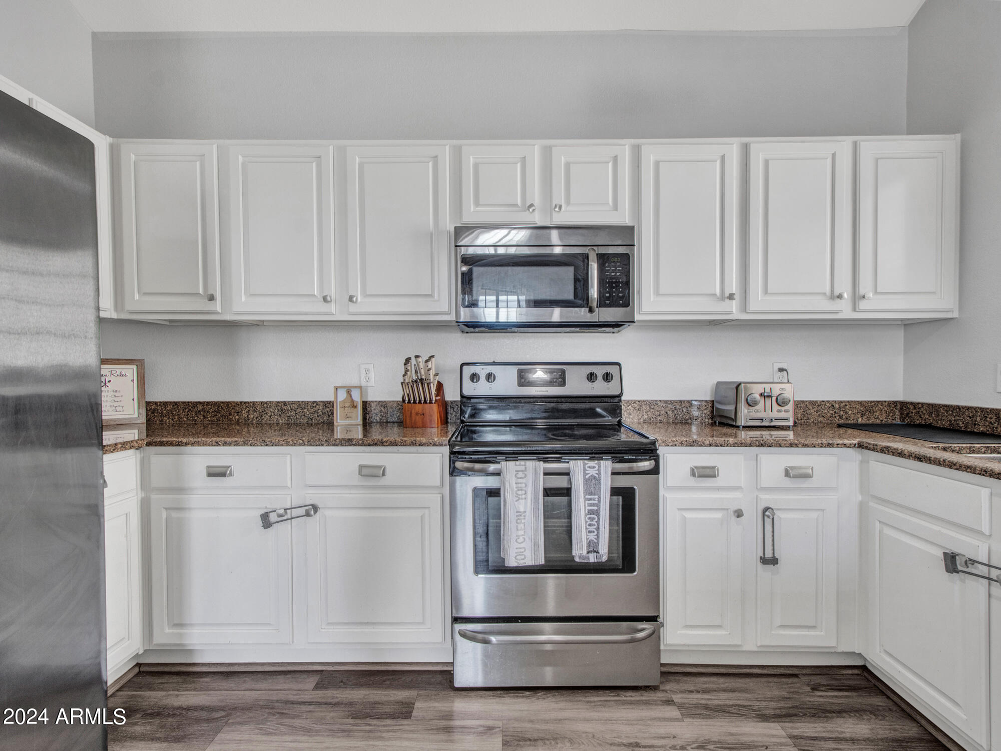 2801 North Litchfield Road, Unit 60 Goodyear, AZ 85395 - Photo 14 of 37 a kitchen with stainless steel appliances granite countertop a stove a sink and white cabinets