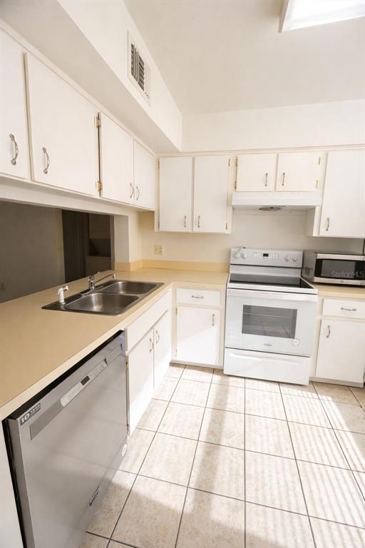 3244 Candle Ridge Drive, Unit 202 Orlando, FL 32822 - Photo 5 of 61 a kitchen with a sink a stove and cabinets