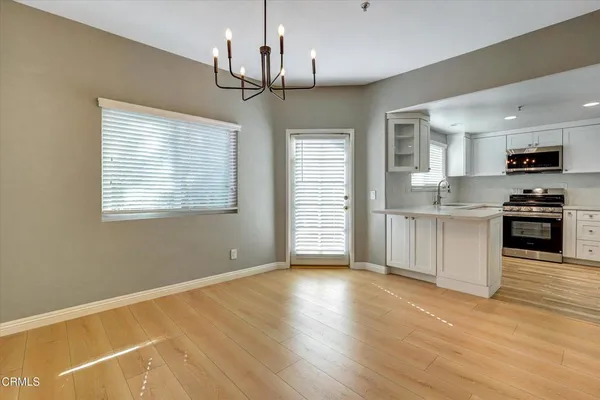 a view of a kitchen with wooden floor a sink a refrigerator and window