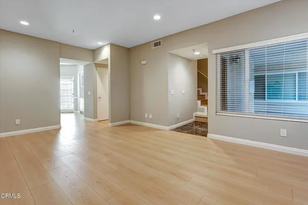 a view of an empty room with wooden floor and a window