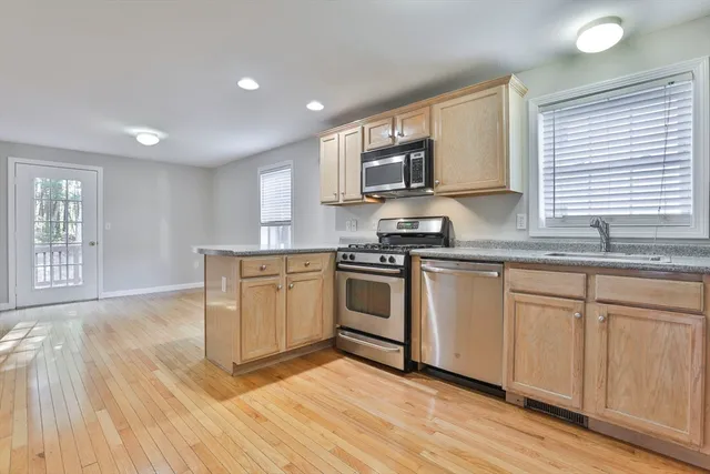 a kitchen with stainless steel appliances granite countertop a stove a sink and white cabinets