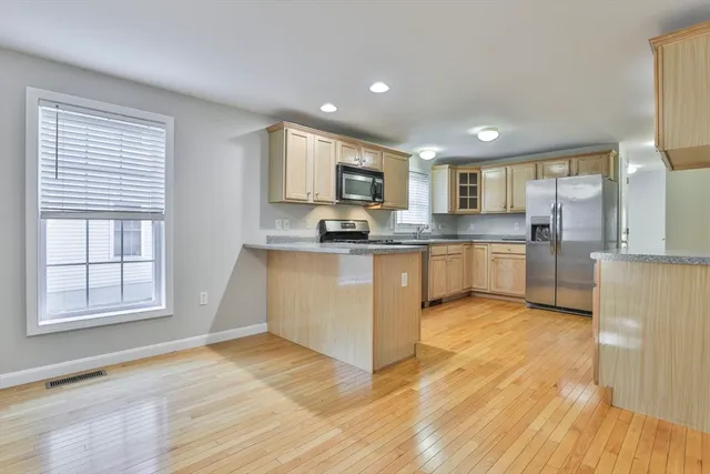 a kitchen with stainless steel appliances granite countertop a stove top oven a sink dishwasher and white cabinets with wooden floor