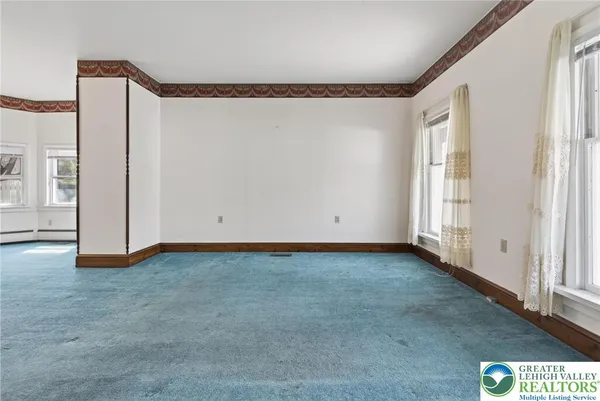 an empty room with chandelier fan and windows