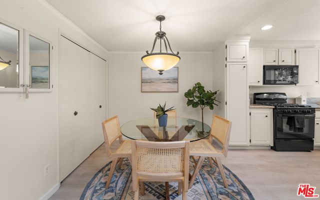 a kitchen with stainless steel appliances a dining table chairs and a refrigerator