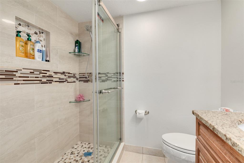 8701 Midnight Pass Road, Unit 106A Sarasota, FL 34242 - Photo 27 of 54 a bathroom with a granite countertop toilet a sink and mirror