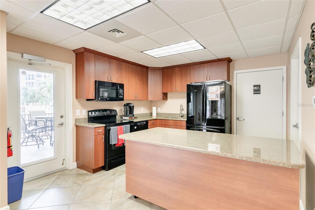 8701 Midnight Pass Road, Unit 106A Sarasota, FL 34242 - Photo 41 of 54 a kitchen with stainless steel appliances kitchen island granite countertop a refrigerator a stove top oven a sink and dishwasher