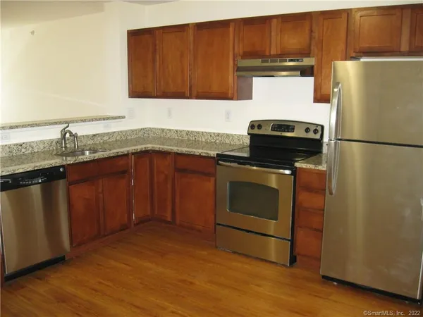 a kitchen with granite countertop a stove a sink and a refrigerator with wooden floor