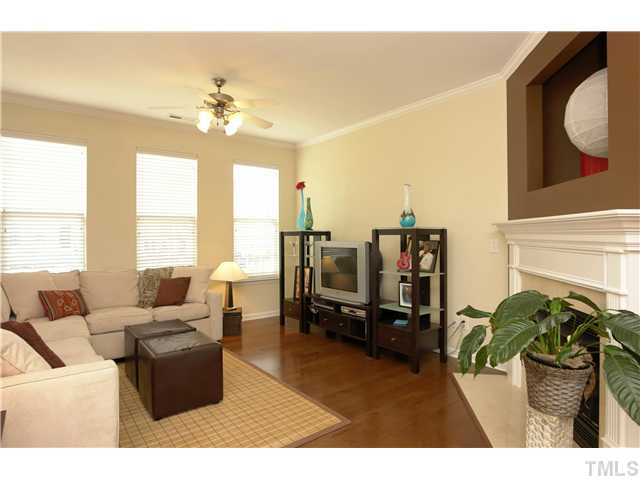 7660 Winners Edge Street Raleigh, NC 27617 - Photo 2 of 12 Spacious LR w/ crown molding, wood blinds, triple front window with great natural lighting, hardwood floors in Gunstock maple, gas fireplace with marble surround and hearth. Upper artist niche or tv corner. Also cable run on side wall for other tv option.