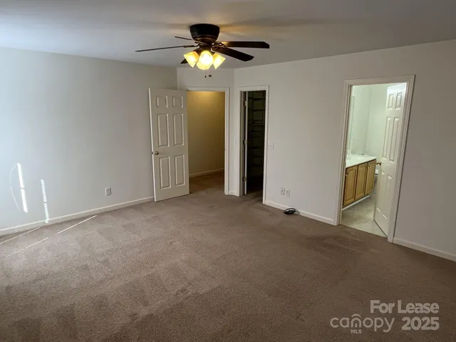 a view of an empty room with a chandelier fan