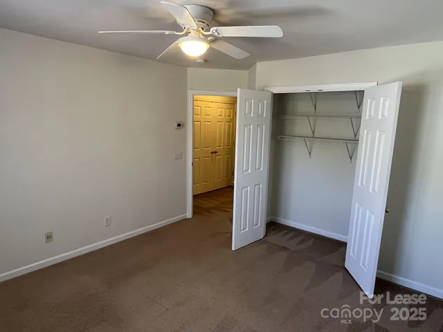 an empty room with closet and a chandelier fan