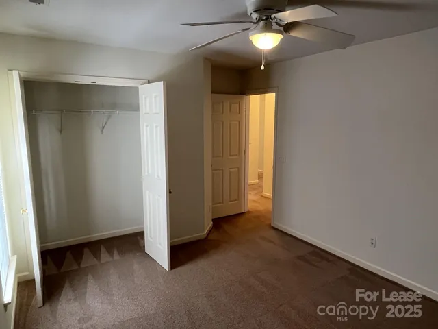 an empty room with closet and a ceiling fan