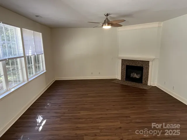 an empty room with wooden floor fireplace and windows