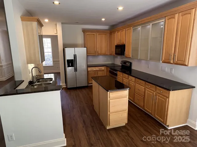 a kitchen with a refrigerator a microwave a sink and wooden floor