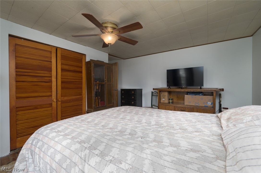 10190 Penniman Road Orwell, OH 44076 - Photo 23 of 24 Bedroom featuring a ceiling fan with integrated lighting, textured ceiling, light-colored walls, wood-finish bi-fold louvered closet doors, and tile flooring
