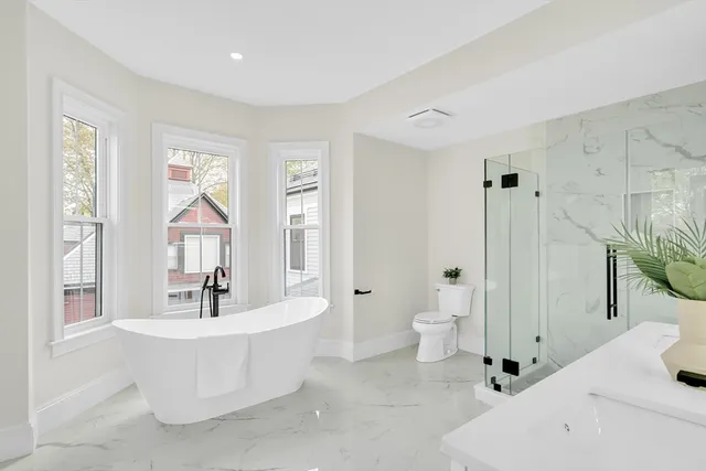 a bathroom with a white tub a sink and a large mirror