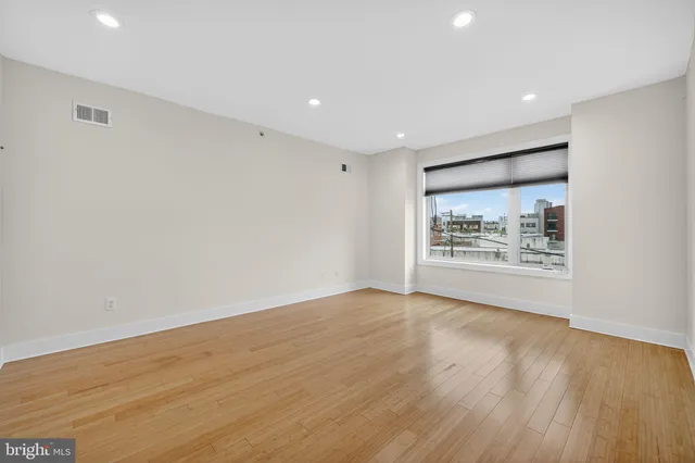 a view of an empty room with wooden floor and a window