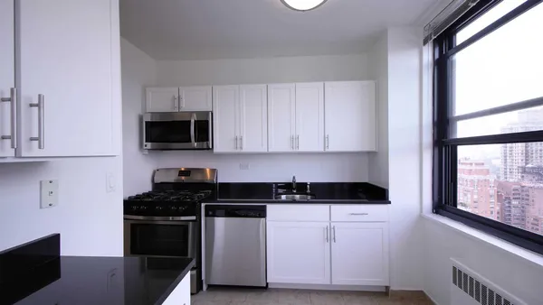 a kitchen with white cabinets a sink and a stove with wooden floor