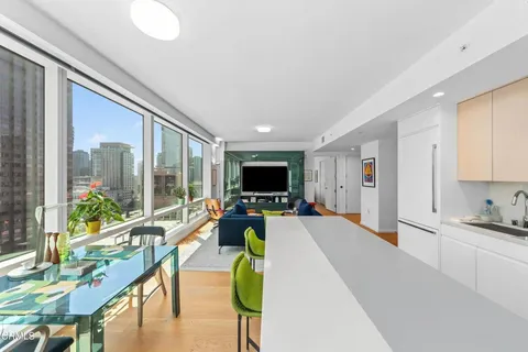 a kitchen with stainless steel appliances granite countertop a stove a sink a refrigerator a dining table and chairs with wooden floor