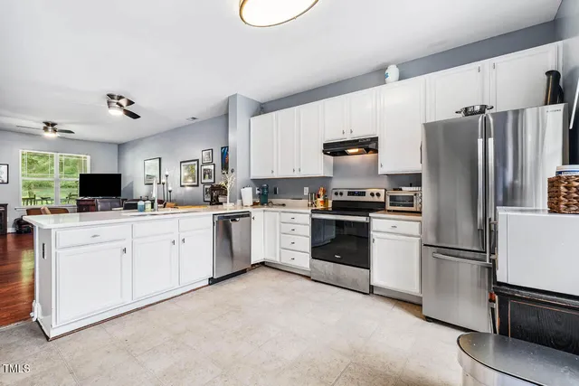 a kitchen with refrigerator a stove and white cabinets