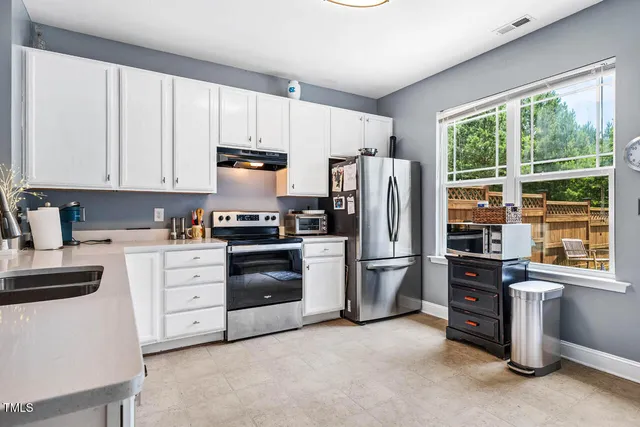 a kitchen with refrigerator a microwave a stove and white cabinets