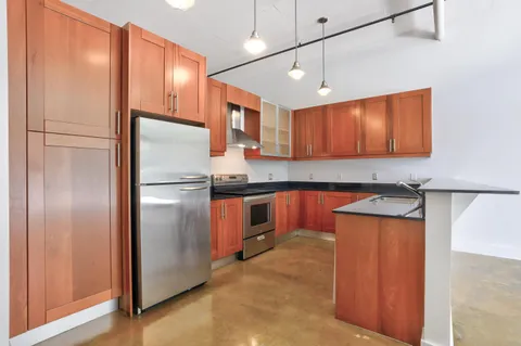 a kitchen with stainless steel appliances granite countertop a refrigerator a sink and a stove