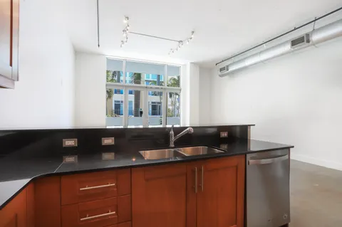 a kitchen with stainless steel appliances granite countertop a refrigerator a sink dishwasher and white countertops with wooden floor