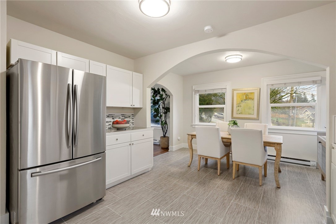 5431 Broadway Everett, WA 98203 - Photo 8 of 22 a kitchen with stainless steel appliances a refrigerator a stove a dining table and chairs with wooden floor