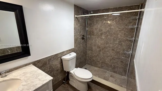 a bathroom with a granite countertop toilet a sink and a mirror