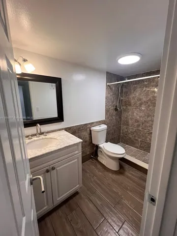 a bathroom with a granite countertop toilet sink and mirror