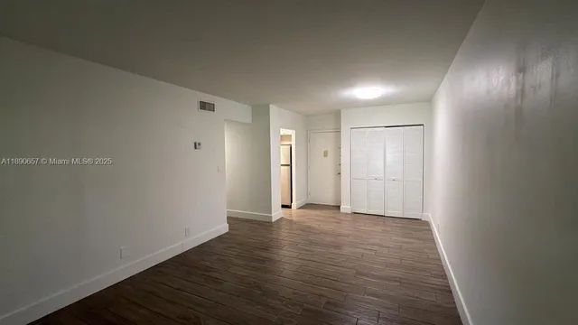 a view of an empty room with wooden floor