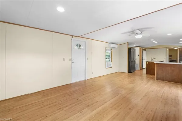 a view of an empty room with wooden floor and a kitchen