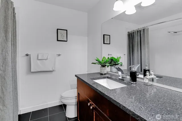 a bathroom with a granite countertop sink a toilet and mirror