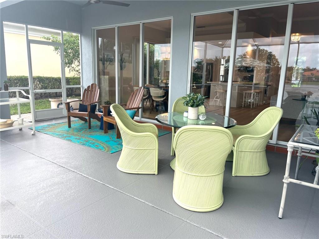 5477 Freeport Lane Naples, FL 34119 - Photo 25 of 36 a living room with patio chairs and a floor to ceiling window
