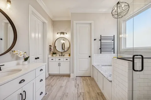 a spacious bathroom with a double vanity sink a mirror a bathtub and window