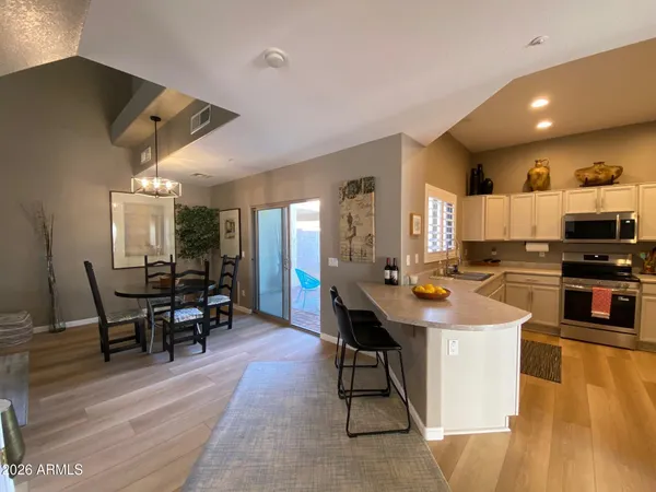 a kitchen with stainless steel appliances kitchen island granite countertop a table chairs sink and cabinets