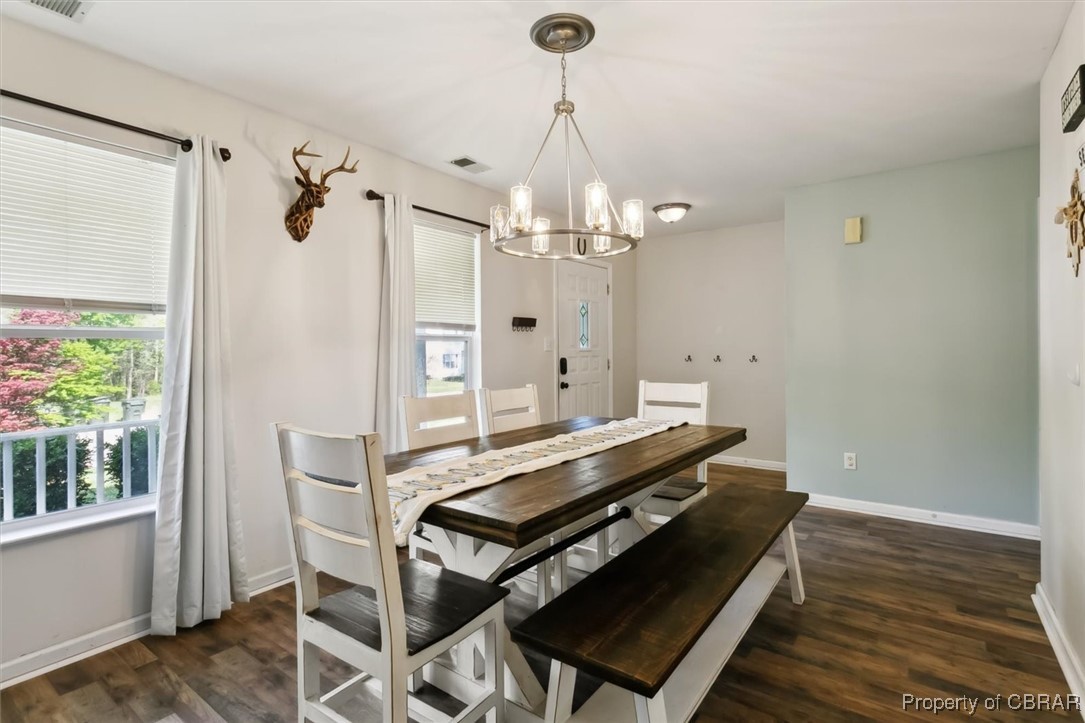 Dining space featuring baseboards, a notable chandelier, dark wood-style floors, and visible vents