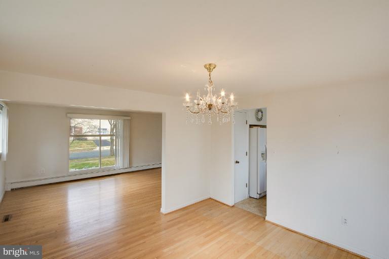 3619 Rusty Rock Road Randallstown, MD 21133 - Photo 12 of 30 an empty room with wooden floor chandelier and windows