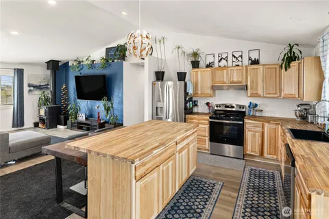 a kitchen with stainless steel appliances a stove refrigerator sink and a fireplace