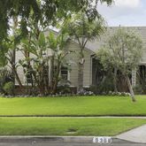 a view of a white house in a big yard with palm trees