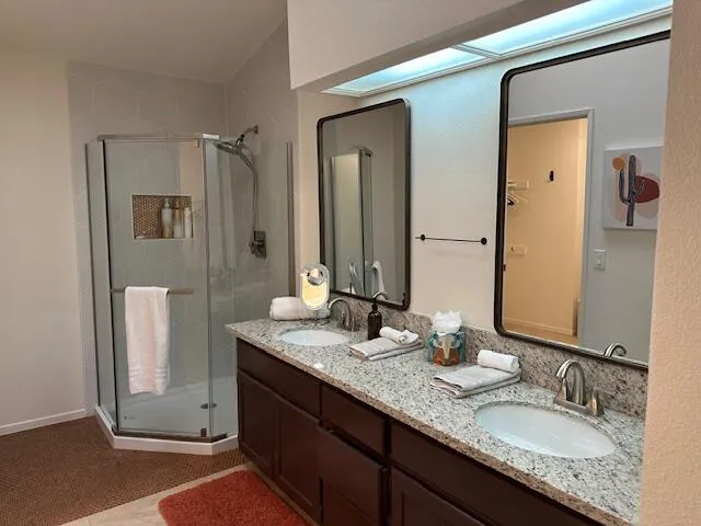 a bathroom with a granite countertop double vanity sink and a mirror