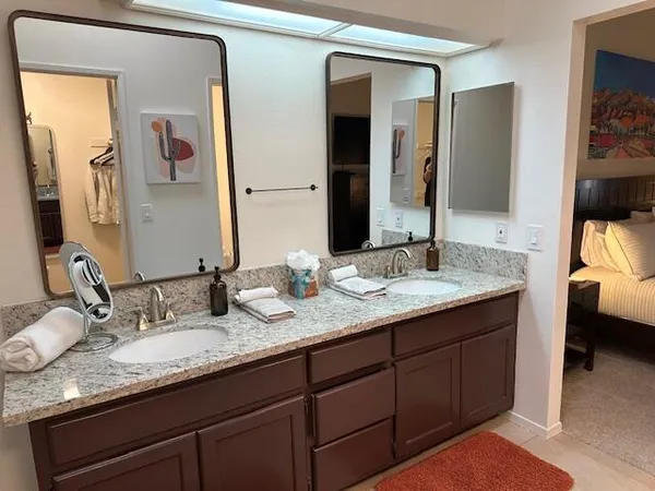 a bathroom with a granite countertop double vanity sink and a mirror