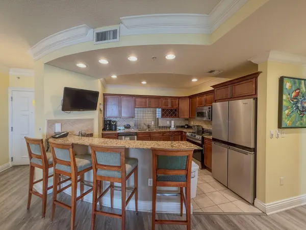 a kitchen with stainless steel appliances granite countertop a dining table chairs refrigerator and microwave