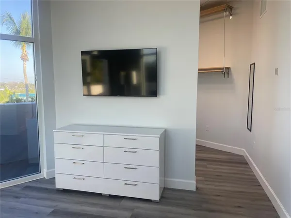 a view of an empty room with wooden floor and windows