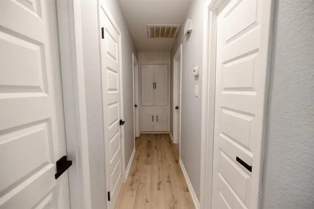 a view of a hallway with wooden floor and a white cabinet