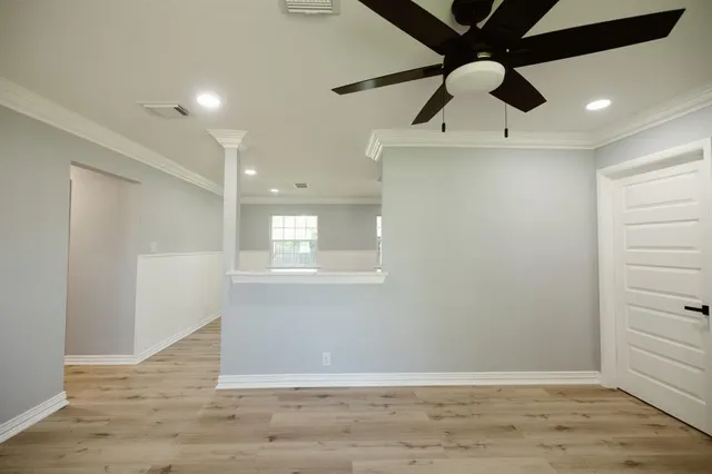 an empty room with wooden floor cabinet and windows