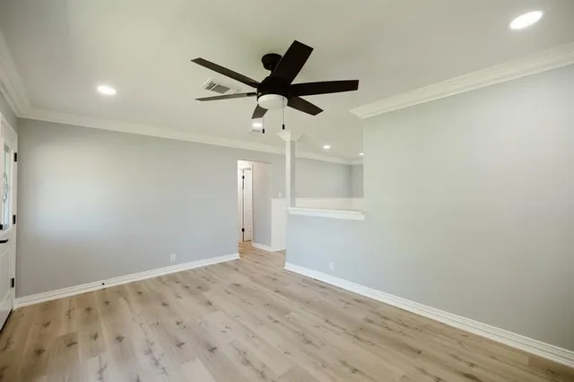 an empty room with wooden floor and a ceiling fan