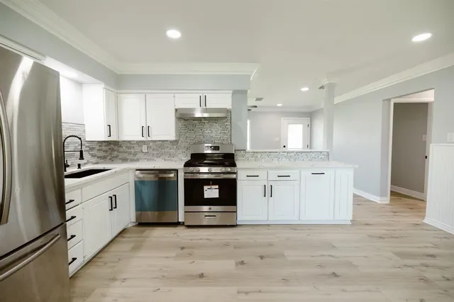 a kitchen with granite countertop white cabinets and stainless steel appliances
