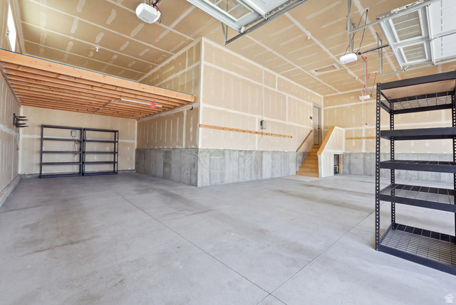 4331 West 475 South West Point, UT 84015 - Photo 37 of 46 Spacious garage with concrete flooring, exposed ceiling joists, wood stairs, and an overhead storage platform