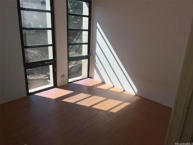 a view of an empty room with wooden floor and a window