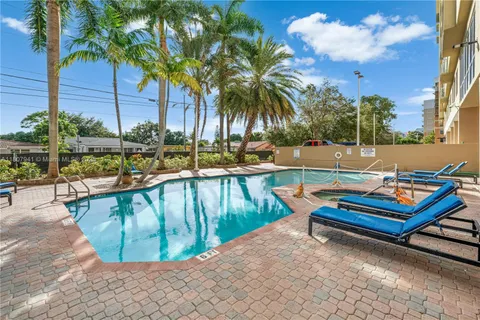 a view of a swimming pool with a lounge chair and palm trees